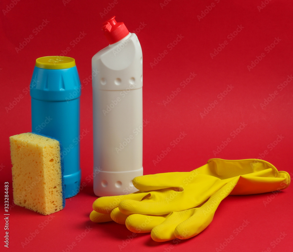 Cleaning concept. Detergent bottles, sponges, gloves on a red background