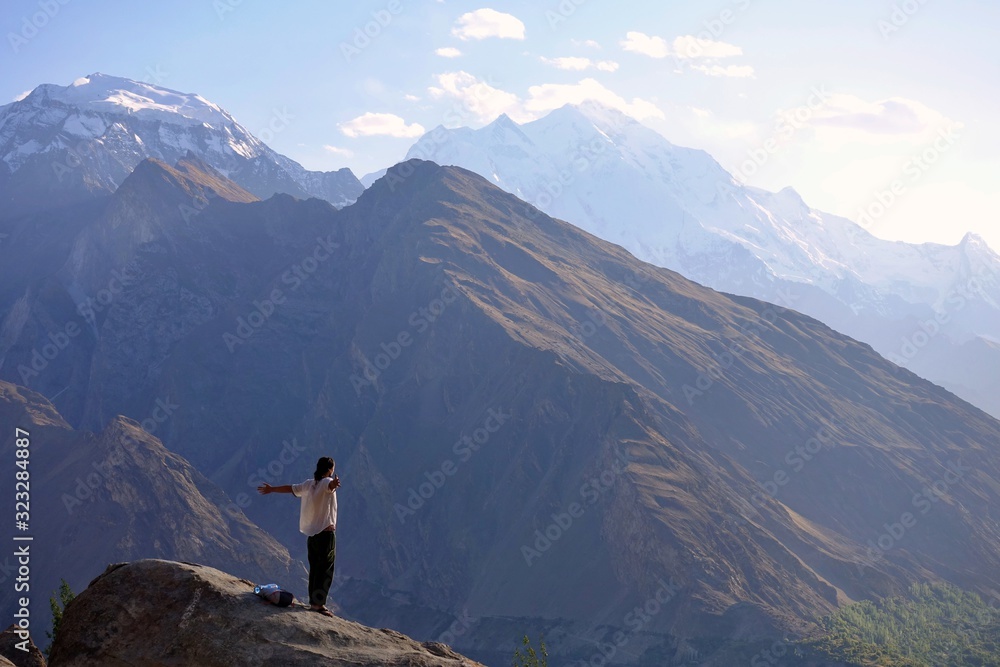 Man in white shirt on a viewpoint in Hunza - View over white peaks of Pakistan