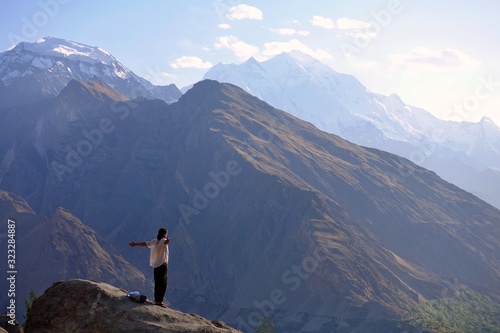 Man in white shirt on a viewpoint in Hunza - View over white peaks of Pakistan