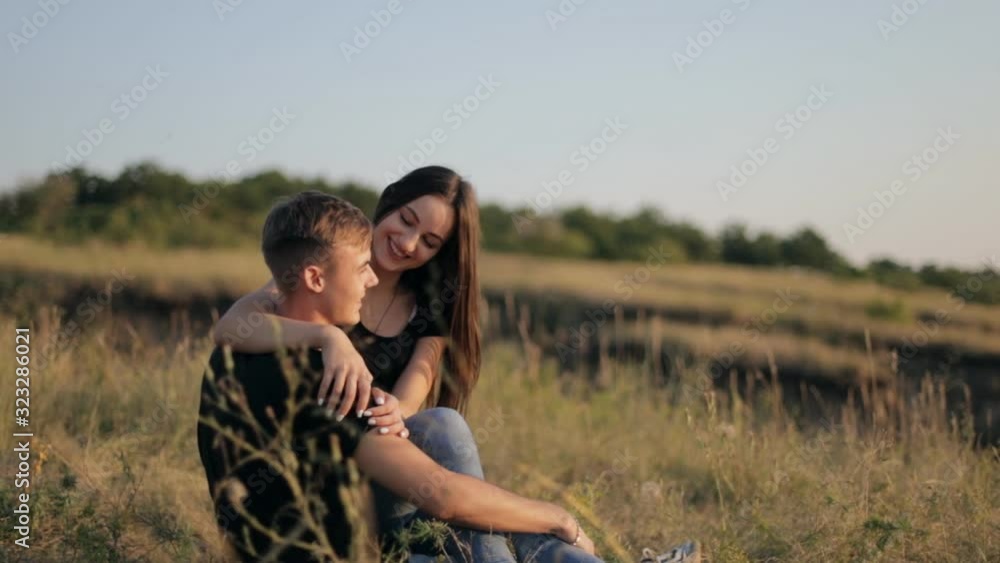 A couple in love enjoys a beautiful sunset. A young and romantic couple is enjoying each other on a romantic summer evening. Happy couple talking and hugging at sunset A couple in love enjoys a beautiful sunset. A young and romantic couple is enjoying each other on a romantic summer evening. Happy couple talking and hugging at sunset