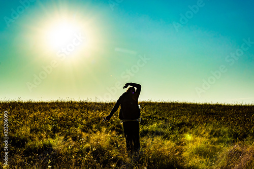 female tourist silhouette with backpack at sunrise in the field