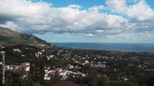 Gimbal pan shot left to right of white andalusian village Mijas pueblo. Panoramic view of cityscape of Mijas in Malaga in winter time under grey cloudy sky