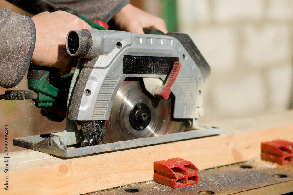 Cutting a standing worker and sawing with a circular saw, industrial construction connecting wooden beams