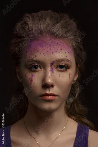 beautiful girl with paint on her face, on a dark background