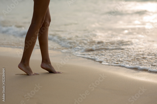beautiful tanned legs of the girl go next to the sea and footprints in the sand