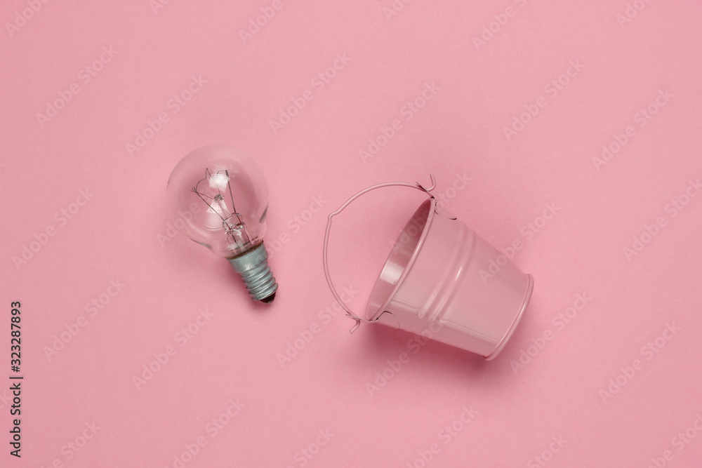 Mini bucket with an incandescent bulb on a pink pastel background. Top view Mini bucket with an incandescent bulb on a pink pastel background. Top view