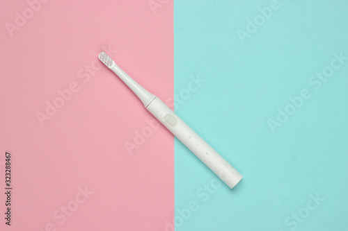 Modern electric toothbrush on a blue pink pastel background. Dental care concept. Top view. Minimalism