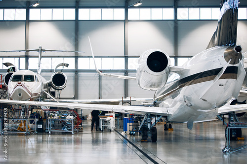 Airplane in a white hangar for maintenance. Inspection and repair works of private jet