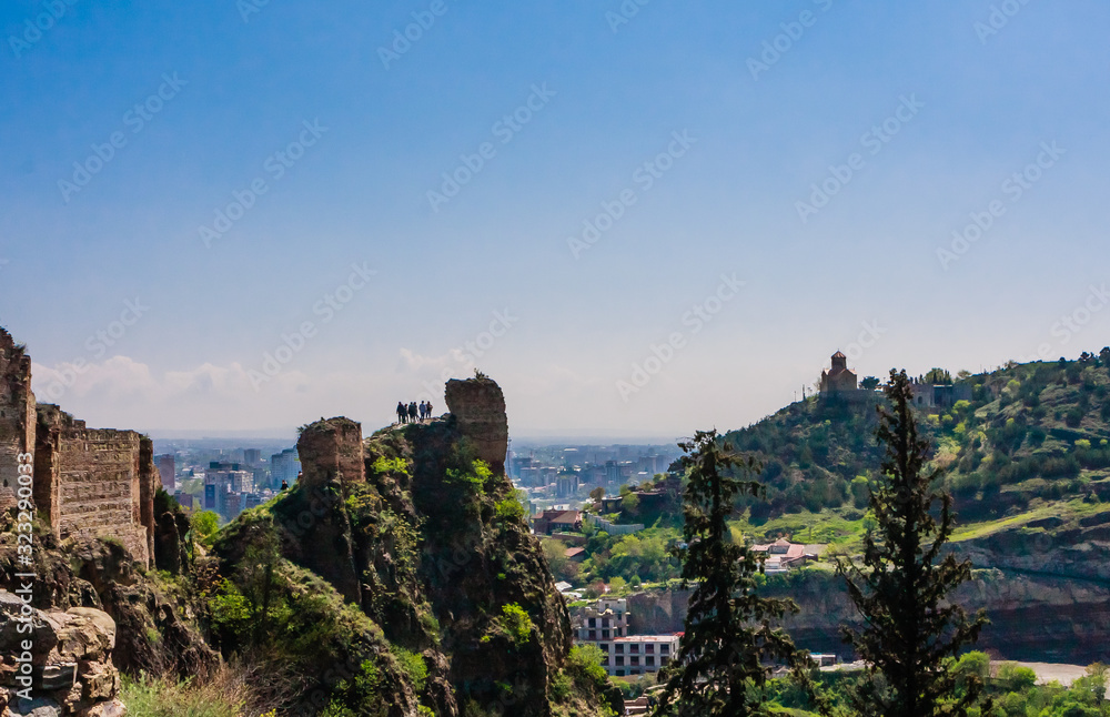 Tourists looking down who climbed ruins at Narikala- an ancient fortress overlooking the capital of Georgia.  Tbilisi, Georgia