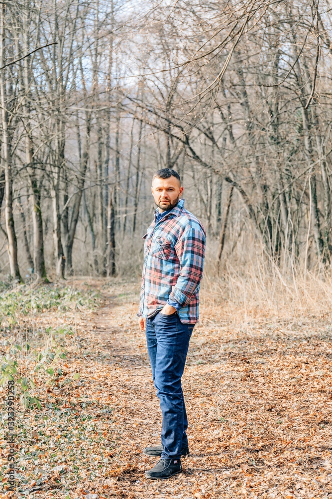 Bearded hipster man with serious face is thinking about something while standing outdoors against autumn fall with copy space, stylish brutal male with trendy look walking in park at sunset. Bearded hipster man with serious face is thinking about something while standing outdoors against autumn fall with copy space, stylish brutal male with trendy look walking in park at sunset.