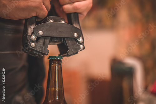 Detail of a tool for closing or bottling beer bottles. Man closing a beer bottle with a cap. Tool for closing craft beer bottle.