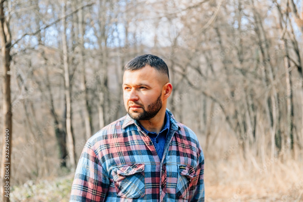 Bearded hipster man with serious face is thinking about something while standing outdoors against autumn fall with copy space, stylish brutal male with trendy look walking in park at sunset. Bearded hipster man with serious face is thinking about something while standing outdoors against autumn fall with copy space, stylish brutal male with trendy look walking in park at sunset.