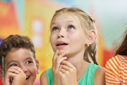 Pensive child looking up. Beautiful little girl looking thoughtful. Kids in play room.