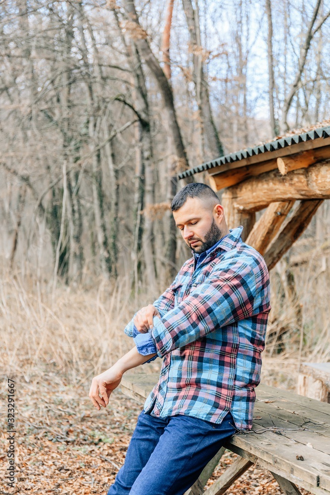 Bearded hipster man with serious face is thinking about something while standing outdoors against autumn fall with copy space, stylish brutal male with trendy look walking in park at sunset. Bearded hipster man with serious face is thinking about something while standing outdoors against autumn fall with copy space, stylish brutal male with trendy look walking in park at sunset.