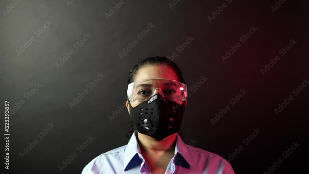 Woman in urban protective or medical mask with glasses, looking at the camera on black background. Coronavirus pathogen outbreak pandemic concept. Virus disease 2019-nCoV protection and prevention. 4k Woman in urban protective or medical mask with glasses, looking at the camera on black background. Coronavirus pathogen outbreak pandemic concept. Virus disease 2019-nCoV protection and prevention. 4k