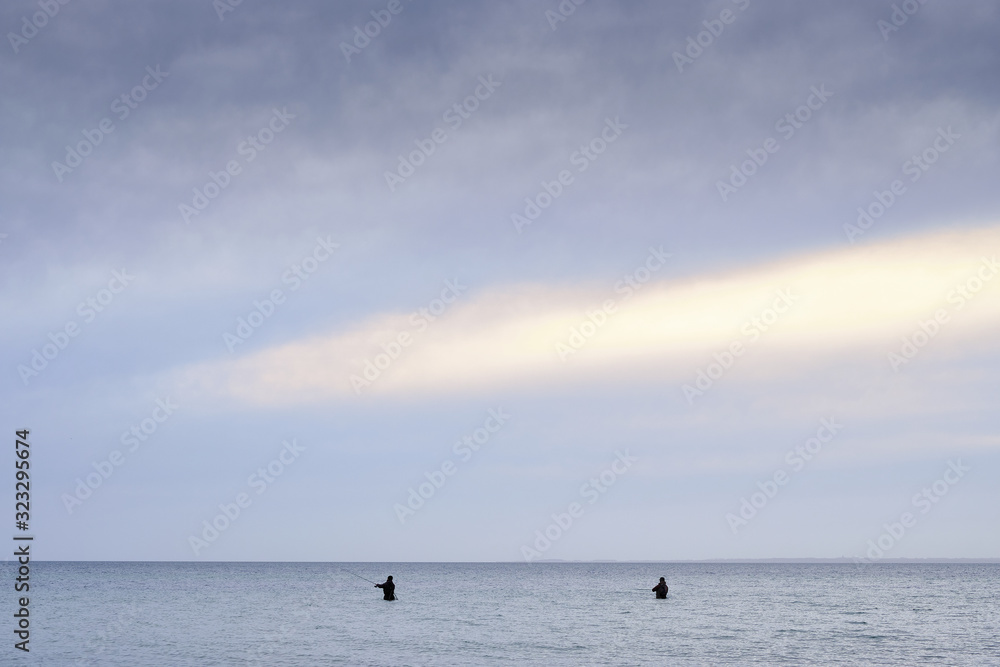 Fishermen standing in the water wishing in the Baltic Sea with horizon 