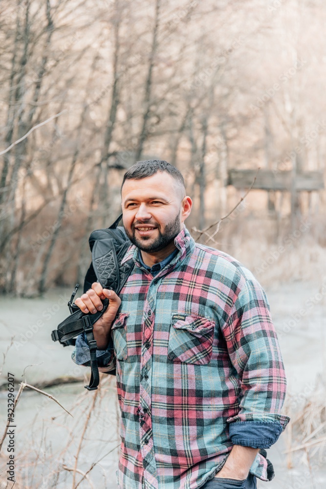 Handsome traveler with backpack in autumnal forest or park. Portrait of a young man isolated on white background.