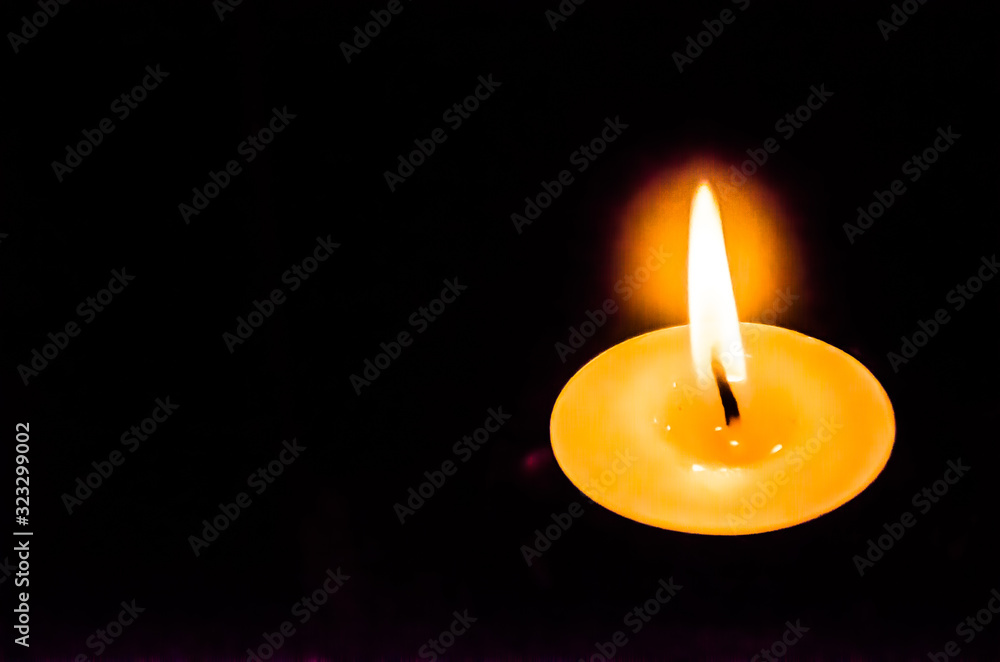A single candle with bright flames in a dark background. A single candle with bright flames in a dark background.