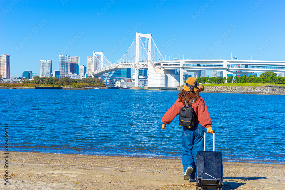 Odaiba island. Japan. Rainbow Bridge in Tokyo. Tourist near the Pacific Gulf. Girl with a suitcase near the rainbow bridge. Trip to the island of Odaiba. Trash island in Japan. Cruise to Japan.