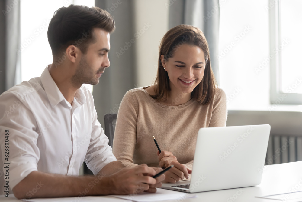 Smiling diverse colleagues work together using laptop Smiling diverse colleagues work together using laptop