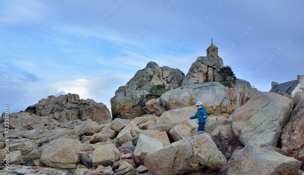Fototapeta premium A young boy who is climbing rocks at seaside