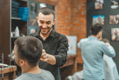 Haircut at the hairdresser. Barber cuts the hair on the client's head. The process of creating hairstyles for men. A man in a barbershop. The near plan. Equipment stylist. Selective focus