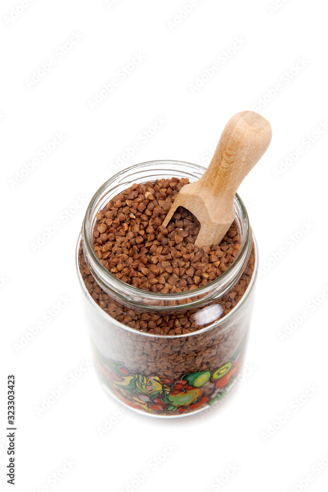 A glass jar with buckwheat and wooden scoop A glass jar with buckwheat and wooden scoop