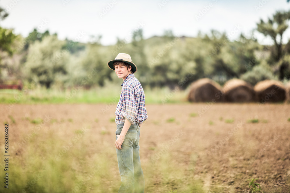 Farmer boy wearing cowboy hat standing in plowed field. Bridger, Montana, USA Farmer boy wearing cowboy hat standing in plowed field. Bridger, Montana, USA