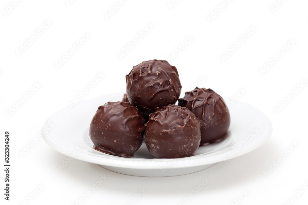 Dark chocolate truffles on a plate, isolated on white background Dark chocolate truffles on a plate, isolated on white background