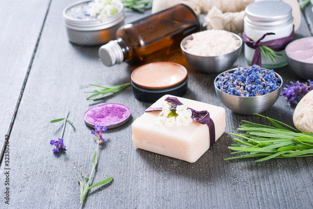 beauty product samples with fresh purple and blue dried lavenders, bath salts and massage pouches on dark wood table background beauty product samples with fresh purple and blue dried lavenders, bath salts and massage pouches on dark wood table background