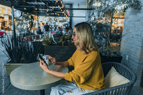 Mujer tomando café en starbucks con celular en mano samsung photo