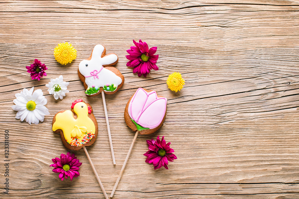 Fototapeta premium Easter cookies, gingerbread in the shape of a rabbit and chicken, spring Easter background with flowers