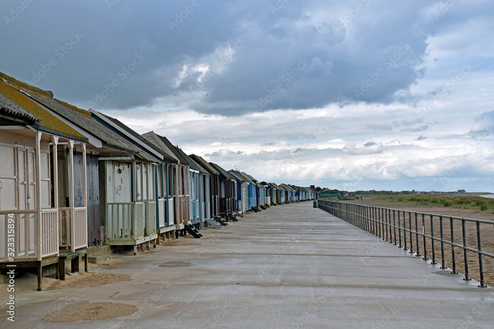 Obraz premium row of beach houses in front of the beach with a cloud sky