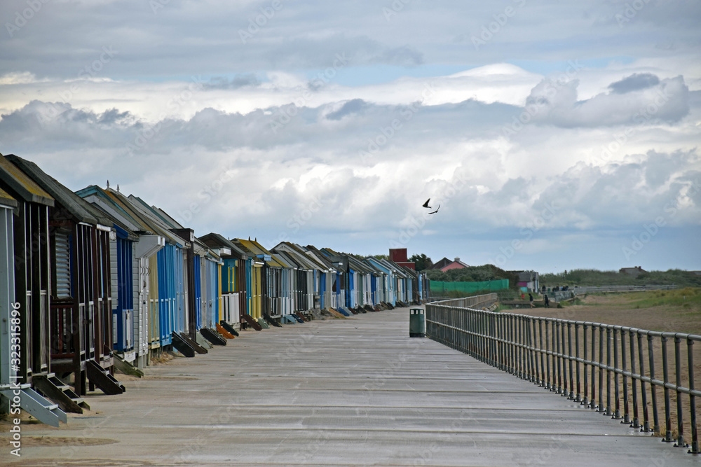 Obraz premium row of beach houses in front of the beach with a cloud sky