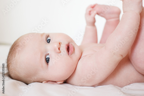 cute baby lies on his back and holds his legs with his hands. On a white background. Selective focus.
