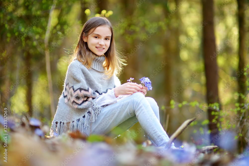 Adorable young girl picking the first flowers of spring in the woods on beautiful sunny spring day. Cute child having fun outdoors. Adorable young girl picking the first flowers of spring in the woods on beautiful sunny spring day. Cute child having fun outdoors.