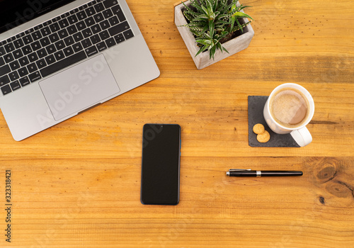 Table Top desk view with pencil a plant, coffee, workspace, mobile display and laptop