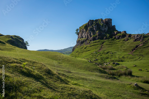 The otherworldly feel of the Fairy Glen, located at the end of a windy road near the Town of Uig, are small round-topped grassy hills with lochans, photographed on a cloudless day.  photo