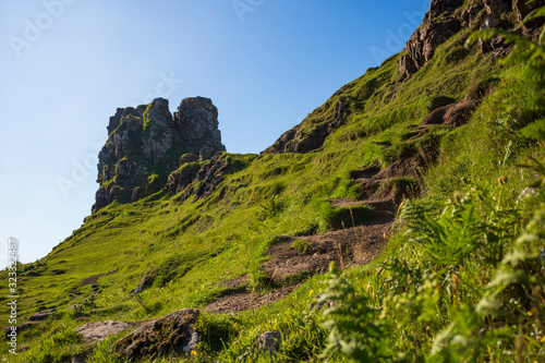 The otherworldly feel of the Fairy Glen, located at the end of a windy road near the Town of Uig, are small round-topped grassy hills with lochans, photographed on a cloudless day.  photo