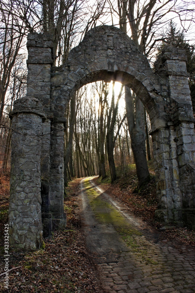 Alter gemauerter Torbogen mit Waldweg im Licht Alter gemauerter Torbogen mit Waldweg im Licht