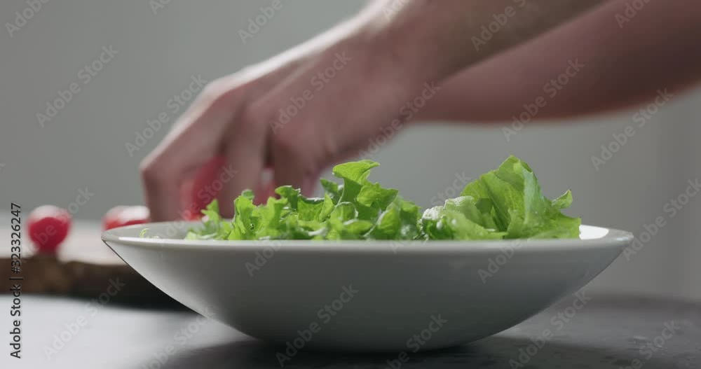 Slow motion add cherry tomatoes to frisee salad leaves into white bowl Slow motion add cherry tomatoes to frisee salad leaves into white bowl