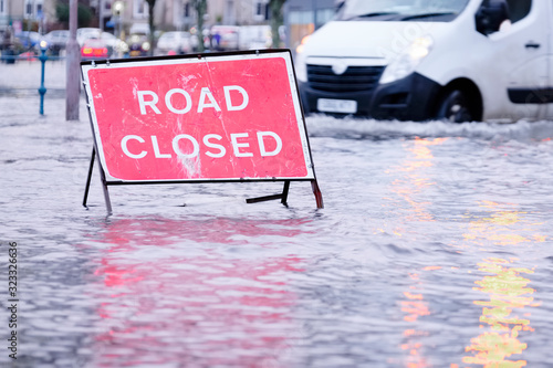 Road flood closed sign under deep water during bad extreme heavy rain storm weather in UK