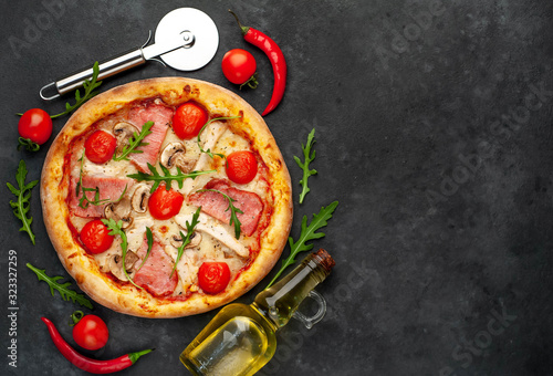 meat pizza with cheese, chicken, ham, mushrooms, tomatoes on a stone background with copy space for your text
