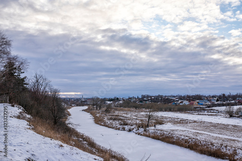 Cloudy day in a small Russian town. Rural landscape with frozen river. 