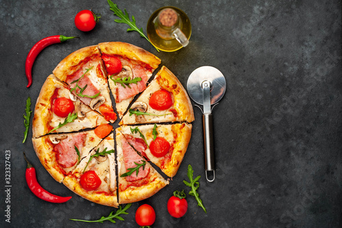 meat pizza with cheese, chicken, ham, mushrooms, tomatoes on a stone background with copy space for your text