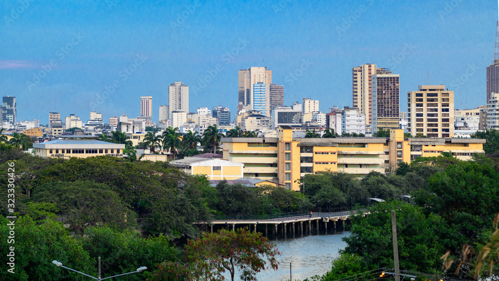 Panoramic view of Guayaquil city, were many of downtown buildings are in the background. Puerto Santa Ana, The Point Building and Del Carmen hill, TV antennas in the background. Trees in foreground.