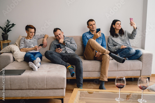Friends sitting on sofa and using smart phone