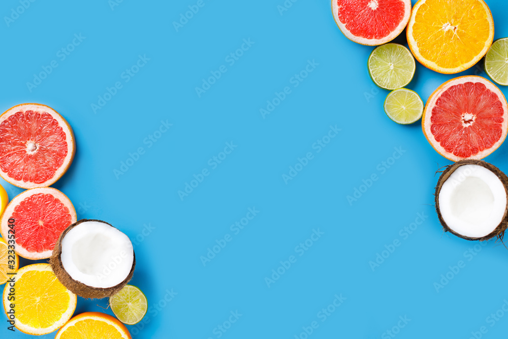 Summer holidays, resort vacation, exotic fruits background. Summertime vibes. Composition with citrus slices on blue surface, copy space