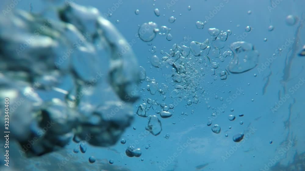 Underwater bubbles rise up in clear blue water Underwater bubbles rise up in clear blue water