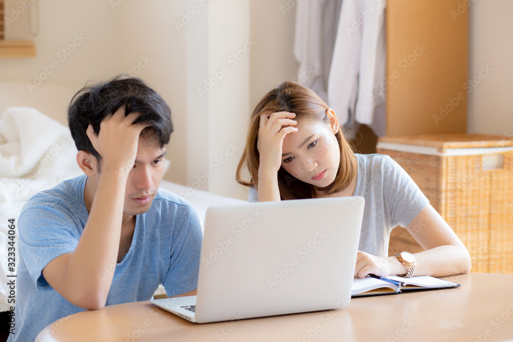 Young asian couple stressed and worried about finance of problem business together, man and woman looking laptop and frustrated, family unhappy and depression about debt, lifestyle concept. Young asian couple stressed and worried about finance of problem business together, man and woman looking laptop and frustrated, family unhappy and depression about debt, lifestyle concept.